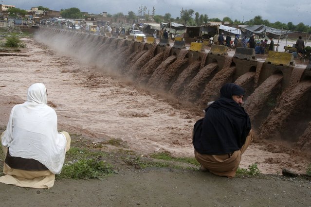 People looks a stream, which is overflowing following heavy rains, on the outskirts of Peshawar, Pakistan, Monday, April 15, 2024. Lightnings and heavy rains killed dozens of people, mostly farmers, across Pakistan in the past three days, officials said Monday, as authorities declared a state of emergency in the country's southwest following an overnight rainfall to avoid any further casualties and damages. (Photo by Muhammad Sajjad/AP Photo)