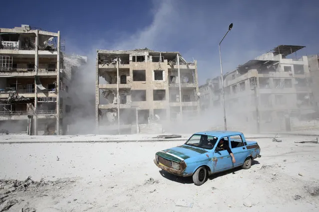 Men drive a car near a site hit by what activists said was an air strike by government forces in Aleppo's al-Ansari al-Sharqi neighbourhood April 2, 2014. (Photo by Ammar Abdullah/Reuters)