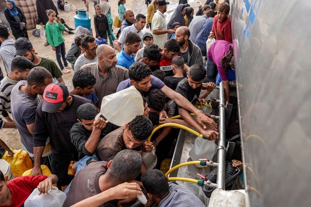 People gather with jerrycans and other containers to collect water from a tanker cistern in Deir el-Balah in the central Gaza Strip on April 30, 2024 amid the ongoing conflict in the Palestinian territory between Israel and the militant group Hamas. (Photo by AFP Photo/Stringer)