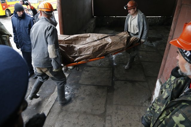 Ukrainian rescuers carry a stretcher with a gas explosion victim's body at the Skochinsky mine in Donetsk, Ukraine, Friday, April 11, 2014. Several people were killed in a gas explosion at a coal mine in eastern Ukraine on Friday, officials said. The Emergency Services Ministry said Seventy-eight people were working in the mine when the blast occurred early Friday morning. They said it was provoked by a sudden release of gas during work in the drilling pits. (Photo by Andrey Basevich/AP Photo)