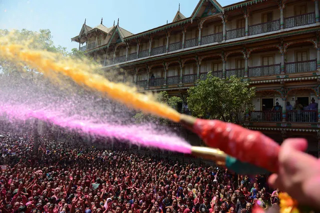 Indian Hindu devotees are sprayed with coloured water by heir to the Kalupur Swaminarayan Temple Lalji Maharaj Shri Vrajendraprasdaji Maharaj as they celebrate the Holi festival at the Swaminarayan Temple in Ahmedabad on March 13, 2017. The Hindu festival of Holi, or the 'Festival of Colours' heralds the arrival of spring and the end of winter. (Photo by Sam Panthaky/AFP Photo)