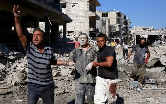 Syrians help a man pulled out from the rubble of a destroyed building following a Russian air strike on July 22, 2019 on Maaret al-Numan in Syria's northwestern Idlib province in the latest violence to plague the opposition bastion, as the Damascus regime and its Russian ally have stepped up their deadly bombardment of Idlib since late April. Sixteen civilians were among 19 people killed and at least 45 others were wounded in the air raid that hit “a wholesale vegetable market in the town of Maaret al-Numan”, according to the Syrian Observatory for Human Rights. The death toll could still rise. Moscow, however, denied it was responsible, calling the reports “fake”. (Photo by Abdulaziz Ketaz/AFP Photo)