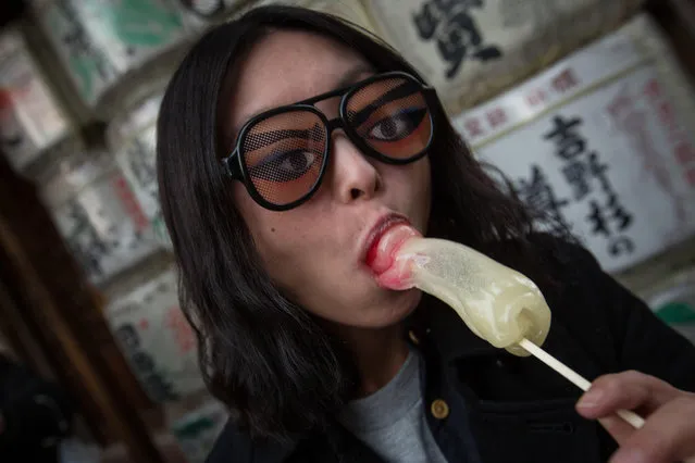 A woman poses for a photo, eating a phallic-shaped candy lollipop during Kanamara Matsuri (Festival of the Steel Phallus) on April 6, 2014 in Kawasaki, Japan. The Kanamara Festival is held annually on the first Sunday of April. The pen*s is the central theme of the festival, focused at the local pen*s-venerating shrine which was once frequented by prostitutes who came to pray for business prosperity and protection against sexually transmitted diseases. (Photo by Chris McGrath/Getty Images)