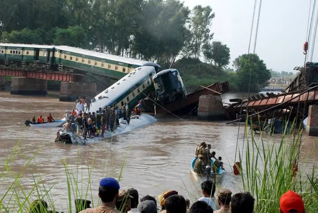 Pakistan Army soldiers and rescue workers gather at the site after a train fell in a canal, near Gujranwala, Pakistan, July 2, 2015. A train carrying hundreds of Pakistan military personnel and their families plunged into a canal on Thursday, killing 12 soldiers, when a bridge collapsed in what the army suspects was sabotage, officials said. (Photo by Reuters/Stringer)