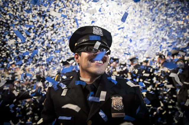 A new member of the New York City Police Department (NYPD) smiles as confetti falls on him at the conclusion of the police academy graduation ceremony at the Theater at Madison Square Garden, March 30, 2017 in New York City. Over 600 new officers were sworn in during the ceremony. (Photo by Drew Angerer/Getty Images)