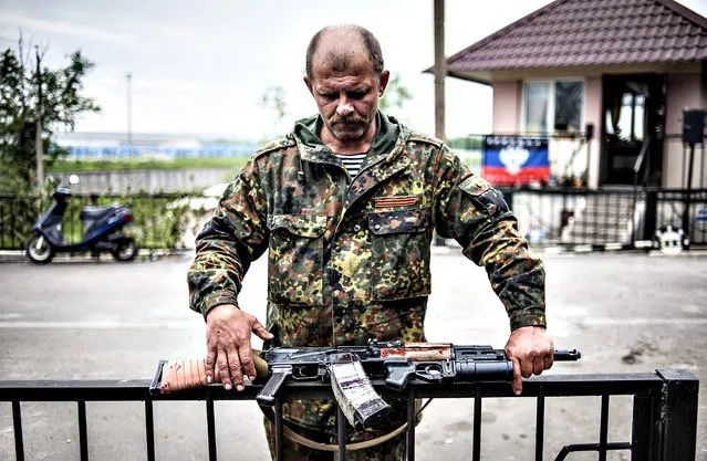 An armed pro-Russian militant stands at a checkpoint near Slaviansk, Ukraine, 12 May 2014. The secession referendum on 11 May, allowed the three million residents of the provinces of Luhansk and Donetsk vote on whether they want to remain part of Ukraine. Russian-speakers and supporters of Moscow have been rallying in the region since March, when a referendum on independence led to Russia's annexation of Crimea. (Photo by Roman Pilipey/EPA)