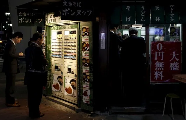 People stand in front of a ticket machine outside an instant noodle restaurant at a business district in Tokyo, Japan, April 30, 2015. (Photo by Yuya Shino/Reuters)