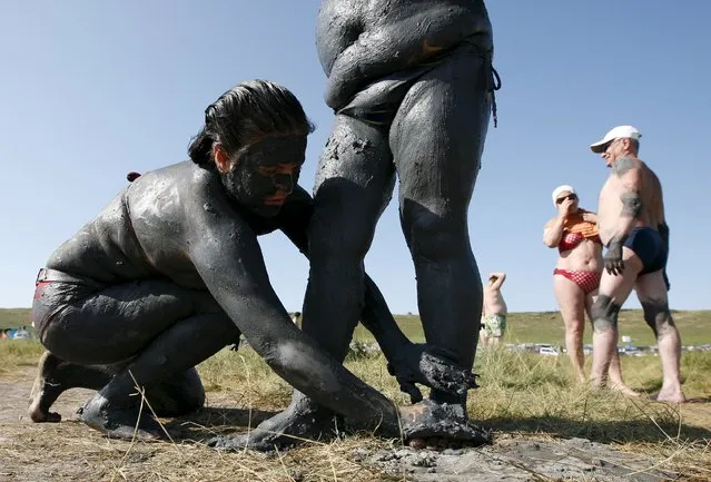 Women smear each other with mineral-rich blue mud on the bank of Tus lake in Khakassia region, southwest of the Siberian city of Krasnoyarsk, Russia, July 18, 2015. During the summer, Russians from different regions travel to lake Tus, famed for the curative properties of its black and blue sediments, to bathe in the salty water and smear themselves with mud. (Photo by Ilya Naymushin/Reuters)