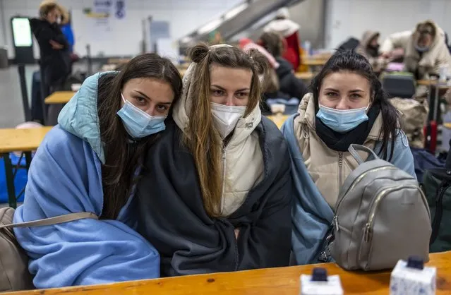 Ola, from left, Sascha and Tanja from the Ukrainian city of Schytomyr wait at the refugee center for refugees from Ukraine at the main train in Berlin, Germany, Sunday, March 13, 20-22. (Photo by Hannibal Hanschke/dpa via AP Photo)