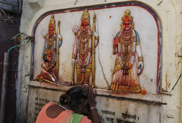 A Hindu pilgrim touches in obeisance an image of Hindu deities Rama, Sita and Lakshman in Ayodhya, India , Saturday, November 9, 2019. India's security forces were on high alert ahead of the Supreme Court's verdict Saturday in a decades-old land title dispute between Muslims and Hindus over plans to build a Hindu temple on a site where Hindu hard-liners demolished a 16th century mosque in 1992, sparking deadly religious riots. (Photo by Rajesh Kumar Singh/AP Photo)