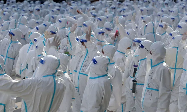 Medical workers in protective suits wave at Changchun residents during a farewell ceremony before returning to Meihekou, where they were dispatched from to help curb the coronavirus disease (COVID-19) outbreak in Changchun, Jilin province, China on April 12, 2022. (Photo by China Daily via Reuters)