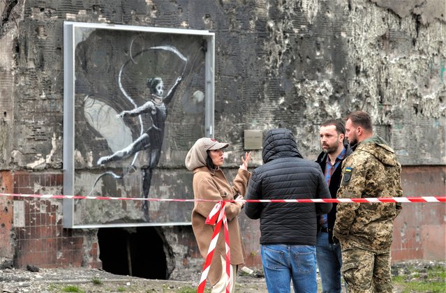 People stand next to a Banksy mural on a damaged building about to be demolished in Irpin, near Kyiv (Kiev), Ukraine, 18 April 2023. The two residential buildings were set to be demolished after being damaged by shelling amid the Russian invasion of Ukraine. A section of one of the two buildings, with a mural created by British street artist Banksy and depicting a rhythmic gymnast wearing a neck brace, will be preserved. Irpin, along with other towns and villages in the northern part of the Kyiv region, were heavily shelled when Russian troops tried to reach the Ukrainian capital between February and March 2022. (Photo by Sergey Dolzhenko/EPA/EFE/Rex Features/Shutterstock)