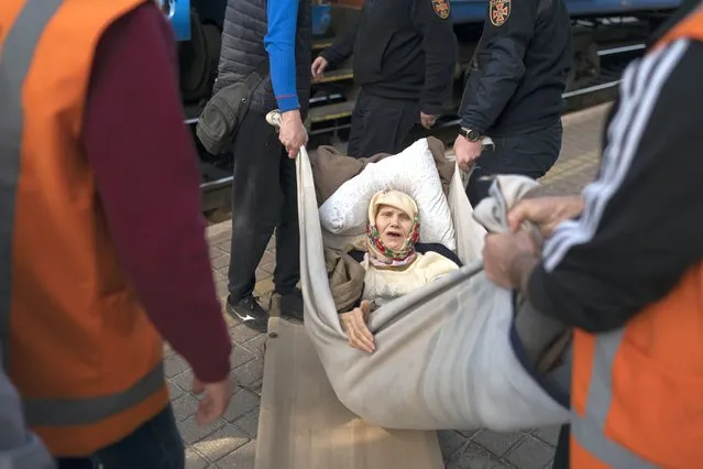 Klavidia, 91, is carried on an improvised stretcher as she boards a train, fleeing the war in Severodonetsk at a train station in Pokrovsk, Ukraine, Monday, April 25, 2022. Russia unleashed a string of attacks against Ukrainian rail and fuel installations Monday, striking crucial infrastructure far from the front line of its eastern offensive. (Photo by Leo Correa/AP Photo)
