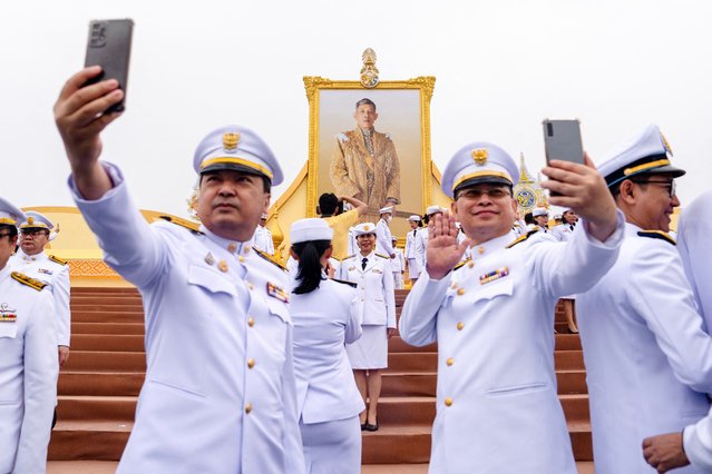 Government officials take selfies in front of a portrait of Thailand’s King Maha Vajiralongkorn during celebrations to mark his 72nd birthday, outside the Grand Palace in Bangkok on July 28, 2024. (Photo by Chanakarn Laosarakham/AFP Photo)