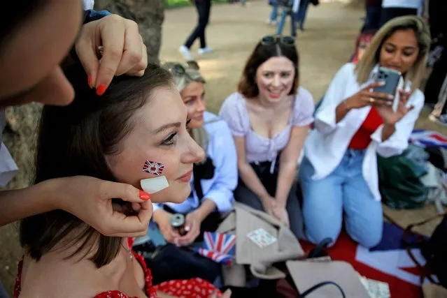 Royal fans have Union flag transfers applied to their faces on The Mall leading to Buckingham Palace in London, Thursday June 2, 2022, on the first of four days of celebrations to mark the Platinum Jubilee. The events over a long holiday weekend in the U.K. are meant to celebrate the monarch's 70 years of service. (Photo by David Cliff/AP Photo)