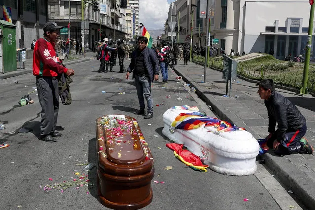 Coffins containing the remains of people killed during clashes between security forces and supporters of former President Evo Morales, lay in the middle of a street after police launched tear gas at a massive funeral procession to disperse anti-government protesters accompanying the coffins into La Paz, Bolivia, Thursday, November 21, 2019. Bolivia has been in a state of turbulence since Morales resigned Nov. 10 after weeks of protests against him over a disputed vote that, according to an international audit, was marred by irregularities. (Photo by Juan Karita/AP Photo)
