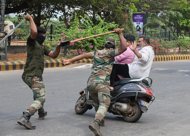 Members of the Karnataka Reserve Police Force swing their sticks to beat two men on a scooter who rode too close to a barricade set up on a street in Mangalore on December 20, 2019, amid heightened security due to protests over India's new citizenship law. Fresh clashes between Indian police and demonstrators erupted on December 20 after more than a week of deadly unrest triggered by a citizenship law seen as anti-Muslim. (Photo by AFP Photo/Stringer)