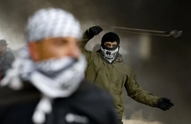 A Palestinian protester uses a slingshot during a demonstration against a US-brokered peace proposal, in the occupied West Bank village of Bilin near Ramallah on February 7, 2020. Israel deployed additional forces in Jerusalem and the occupied West Bank ahead of weekly Muslim Friday prayers, a day after a deadly uptick in violence. The rise in violence comes a week after US President Donald Trump released a long-delayed plan for the Middle East that angered the Palestinians. (Photo by Abbas Momani/AFP Photo)