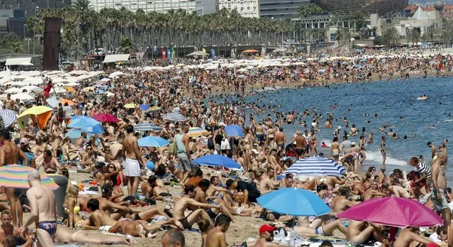 People cool off at Sant Sebastia beach in Barceloneta neighbourhood in Barcelona, Spain, August 16, 2015. Spanish consumer prices rose slightly in July from a year earlier, the second increase in a row as the economy strengthened and retailers and hotels hiked their charges. The prices of package holidays were up from a year ago in July, National Statistics Institute (INE) said. Hotel, cafe and restaurant prices were up 0.9 percent year-on-year in July when the summer tourism season got underway. (Photo by Albert Gea/Reuters)