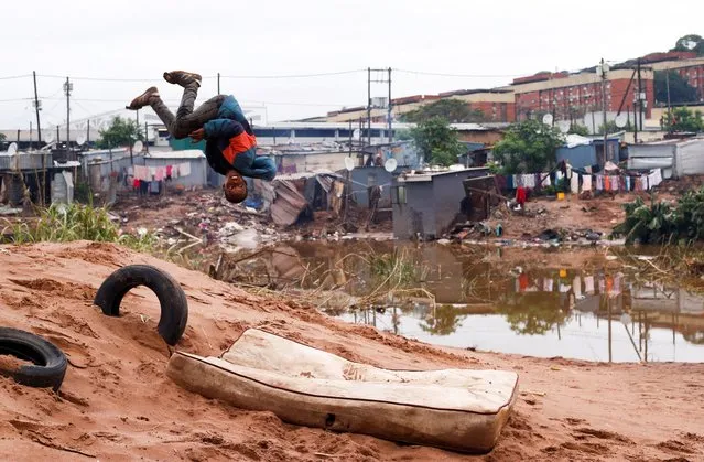 A child does a back flip onto an old mattress among the destruction caused by flooding in Umlazi near Durban, South Africa, April 16, 2022. (Photo by Rogan Ward/Reuters)