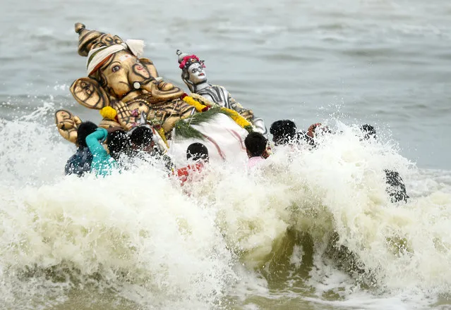 Indian devotees immerse an idol of the elephant-headed Hindu god Ganesh in the Indian ocean at Pattinapakkam beach in Chennai on August 27, 2017. The Ganesh Chaturthi festival, a popular 11-day religious festival which is annually celebrated across India, runs this year from August 25 to September 5, and culminates with the immersion of idols of Ganesh in water. (Photo by Arun Sankar/AFP Photo)