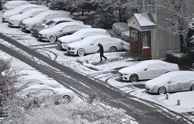 A worker clears snow in front of an apartment building after a snowfall in Goyang on November 27, 2024. (Photo by Jung Yeon-Je/AFP Photo)