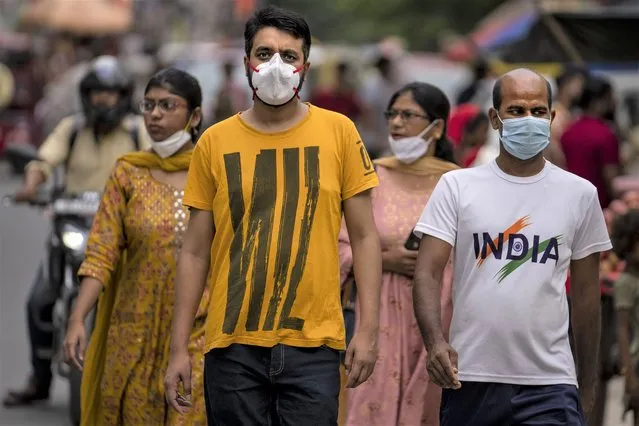 People wearing masks as a precaution against the coronavirus walk through a market in New Delhi, India, Thursday, August 11, 2022. The Indian capital reintroduced public mask mandates on Thursday as COVID-19 cases continue to rise across the country. (Photo by Altaf Qadri/AP Photo)