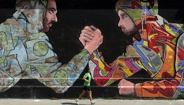A jogger runs past a mural on a wall on a sunny summer day in Vienna, August 21, 2014. (Photo by Heinz-Peter Bader/Reuters)
