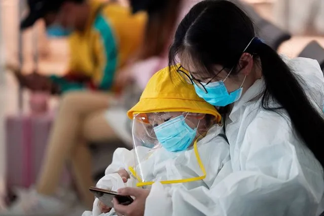 A woman and a child in protective suits check a mobile phone at Wuhan Tianhe International Airport after the lockdown was lifted in Wuhan, the capital of Hubei province and China's epicentre of the novel coronavirus disease (COVID-19) outbreak, April 10, 2020. (Photo by Aly Song/Reuters)