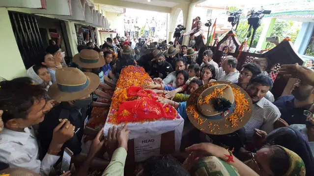 People stretch out their arms to touch the coffin containing the remains of Chandra Shekhar, an Indian army soldier who went missing 38 years ago, in Haldwani, India, Wednesday, August 17, 2022. The soldier and 17 other colleagues were occupying a ridge on Siachen Glacier, high in the Karakoram range in disputed Kashmir's Ladakh region, in May 1984 when they were hit by an avalanche, officials said. (Photo by AP Photo/Stringer)