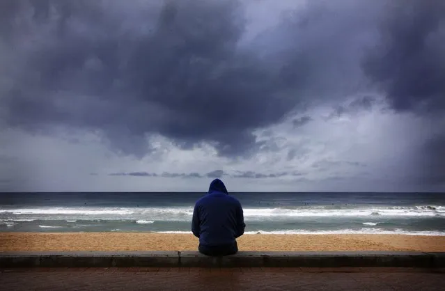 A surfer looks at waves as storm clouds move in from the Pacific Ocean at Sydney's Manly Beach August 26, 2014. The Australian Weather Bureau reported today that despite tropical Pacific Ocean temperatures remaining at neutral levels, models suggest El Nino development remains possible during the coming months, adding that weakening trade winds over the Pacific Ocean earlier in August produced little warming of tropical sea surface temperatures. (Photo by David Gray/Reuters)