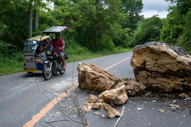 A tricycle passes by fallen rocks in the aftermath of an earthquake in Bangued, Abra province, Philippines, July 28, 2022. (Photo by Lisa Marie David/Reuters)