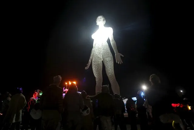 Participants gather at the base of the art installation R-Evolution during the Burning Man 2015 “Carnival of Mirrors” arts and music festival in the Black Rock Desert of Nevada, September 3, 2015. (Photo by Jim Urquhart/Reuters)