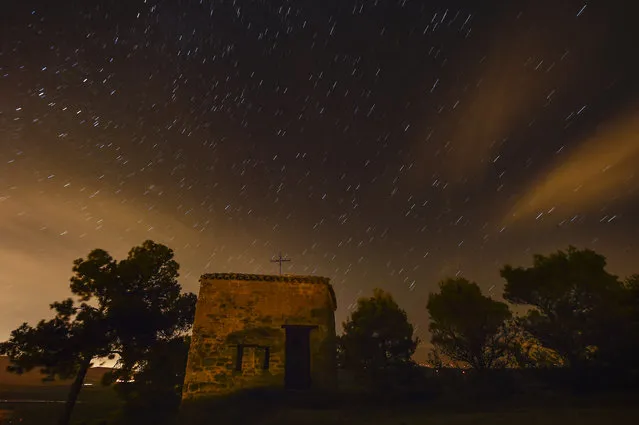 Stars seen as streaks from a long camera exposure are seen behind Arnotegui Hermitage, in Obanos, northern Spain, Tuesday, August 11, 2015. Some Catholics refer to the Perseids as the “tears of Saint Lawrence”, since 10 August is the date of that saint's martyrdom. (Photo by Alvaro Barrientos/AP Photo)