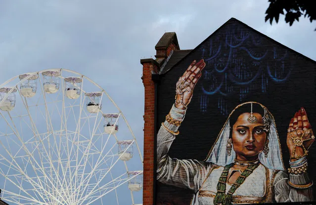 People ride on a ferris wheel behind a giant mural during the Diwali lights switch on in Leicester, Britain October 8, 2017. (Photo by Darren Staples/Reuters)