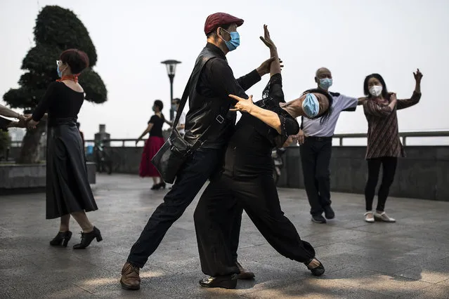 Residents wear masks while practicing dance near the Yangtze River on May 01, 2020 in Wuhan, China. The emergency response level of public health in Hubei Province has been lowered from the highest level to the second-highest level as the government begins lifting outbound travel restrictions after almost 11 weeks of lockdown due to COVID-19. (Photo by Getty Images/China Stringer Network)