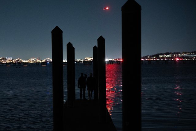 Two people stand on the end of a dock at the marina on Daingerfield Island as emergency crews search for survivors in Arlington, Va. on January 29, 2025. (Photo by Luke Johnson for The Washington Post)