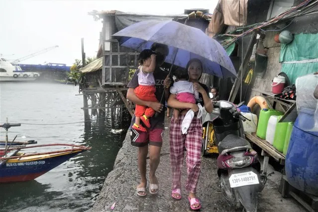 Residents carry their children as they evacuate to safer grounds to prepare for the coming of Typhoon Noru at the seaside slum district of Tondo in Manila, Philippines, Sunday, September 25, 2022. (Photo by Aaron Favila/AP Photo)