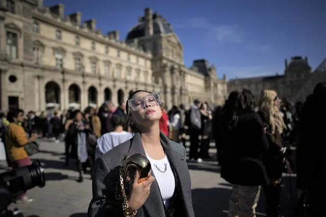A woman takes the sun in the courtyard of the Louvre museum during Louis Vuitton ready-to-wear Spring/Summer 2023 fashion collection presented Tuesday, October 4, 2022 in Paris. (Photo by Christophe Ena/AP Photo)