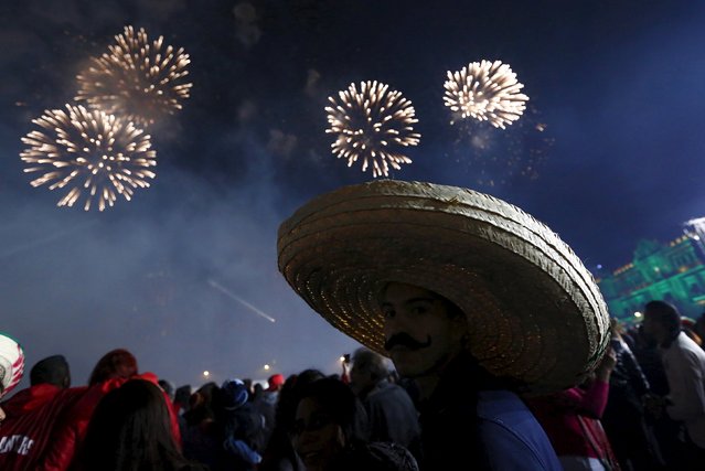 A man wears a traditional Mexican hat as he enjoys fireworks after the “Cry of Independence” by Mexico's President Enrique Pena Nieto, on the 205th anniversary of the day rebel priest Manuel Hidalgo set the country on the path to independence, in Mexico City, September 15, 2015. Mexico celebrates the anniversary of its independence from Spain on September 16. (Photo by Edgard Garrido/Reuters)
