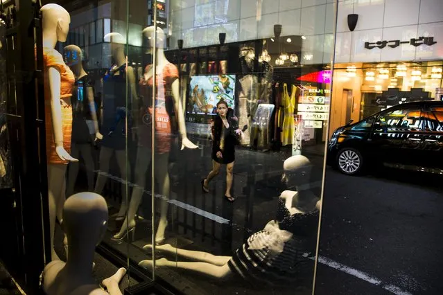 A woman walks past mannequins in a window in Shinjuku's nightlife district of Kabukicho in Tokyo, August 27, 2015. (Photo by Thomas Peter/Reuters)