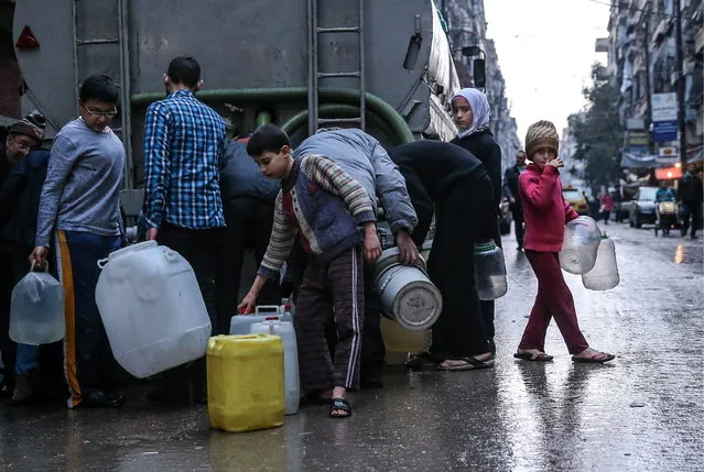 Children fill containers with drinking water from a tanker in Salah al-Din, Aleppo, Syria, on March 5, 2016. (Photo by Valery Sharifulin/TASS via Getty Images)