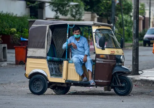 An auto-rickshaw driver waits for customers on a street in Karachi on July 4, 2020. (Photo by Rizwan Tabassum/AFP Photo)