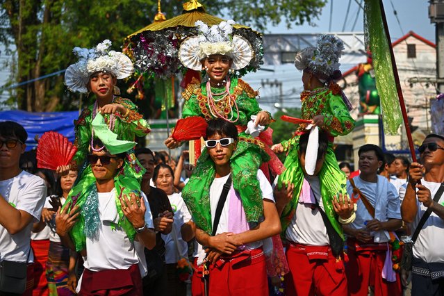 This photograph taken on March 28, 2025 shows young ethnic Shan boys wearing shimmering colourful dresses being carried by their family members during the annual Poy Sang Long procession, a traditional rite of passage ceremony for young boys to be initiated as novice Buddhist monks at the Wat Ku Tao Buddhist temple in Chiang Mai in northern Thailand. Dressed in flowers, finery and makeup, scores of boys were paraded around a temple in Thailand before having their heads shaved – a symbolic start to a centuries-old Shan monkhood ordination. (Photo by Manan Vatsyayana/AFP Photo)