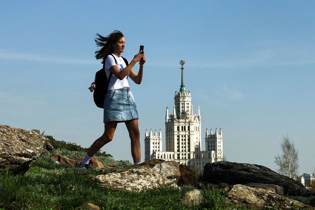 A woman walks in the Zaryadye Park, with a Soviet era skyscraper seen in the background, during a sunny day in Moscow, Russia on April 21, 2025. (Photo by Evgenia Novozhenina/Reuters)