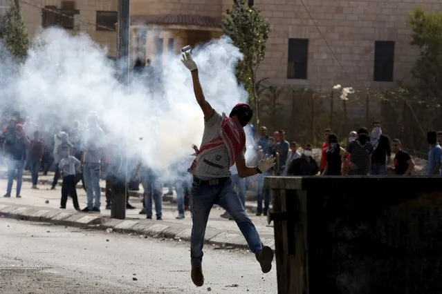 A Palestinian throws back a tear gas canister fired by Israeli troops during clashes in the occupied West Bank city of Bethlehem October 6, 2015. Palestinian President Mahmoud Abbas said on Tuesday he did not want a spike in deadly violence in East Jerusalem and the Israeli-occupied West Bank to spiral into armed confrontation with Israel. REUTERS/Mussa Qawasma