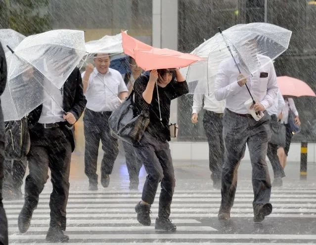 Pedestrians make their way through a street in the heavy rain in Nagoya, central Japan, while a typhoon approaches east along Japan's Pacific coast toward central Japan and Tokyo, Tuesday, September 20, 2016. (Photo by Yoshiaki Sakamoto/Kyodo News via AP Photo)