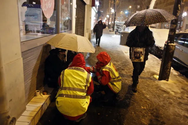 Volunteers from talk with an homeless man in Boulogne Billancourt, west of Paris, Tuesday, February 6, 2018. France's national weather agency Meteo France said Monday about half the country is on alert for dangerous levels of snow and ice. (Photo by Thibault Camus/AP Photo)