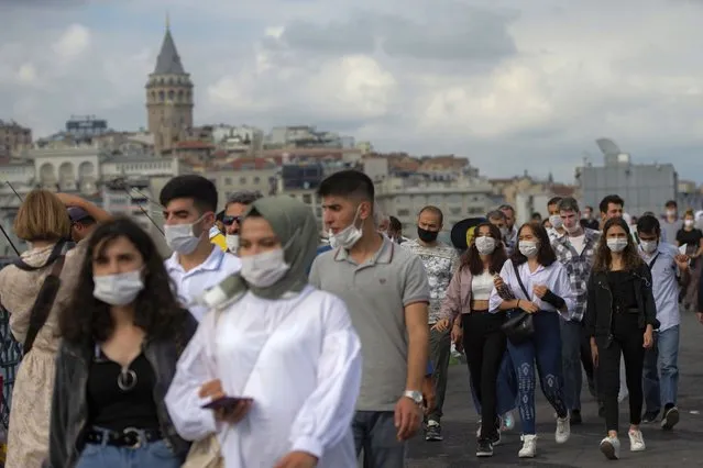 Backdropped by Istanbul's iconic Galata Tower, people wearing masks for protection against the spread of coronavirus, walk over Eminonu bridge in Istanbul, Friday, September 11, 2020. Turkey is getting tough on people who flout self-isolation rules despite testing positive for the coronavirus. An Interior Ministry circular sent to the country's 81 provinces on Friday said people caught leaving their homes despite isolation orders will be quarantined and supervised at state-owned dormitories or hostels. (Photo by Yasin Akgul/AP Photo)