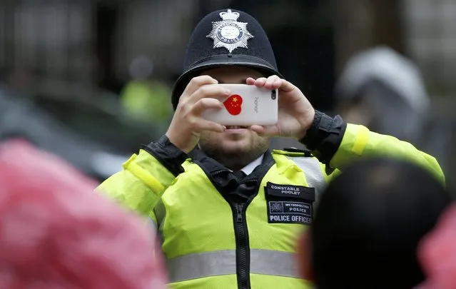 A police officer takes a picture for supporters of China's President Xi Jinping outside Downing Street in central London, Britain, October 21, 2015. (Photo by Peter Nicholls/Reuters)